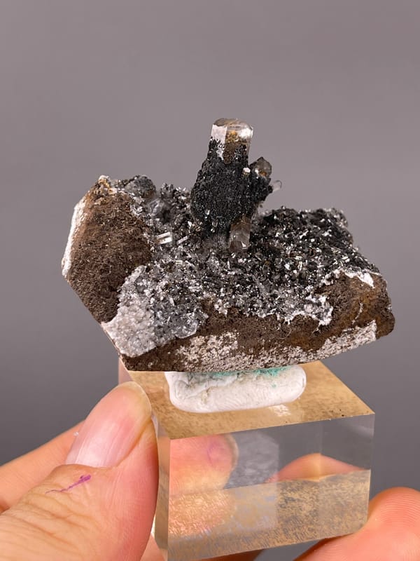 Dark prismatic crystals with brassy coating visible on calcite specimen from Longyan, Fujian, China