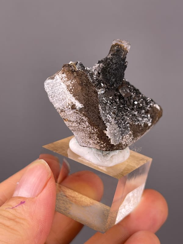 Dark prismatic crystals with brassy coating on natural calcite specimen from Longyan, Fujian, China