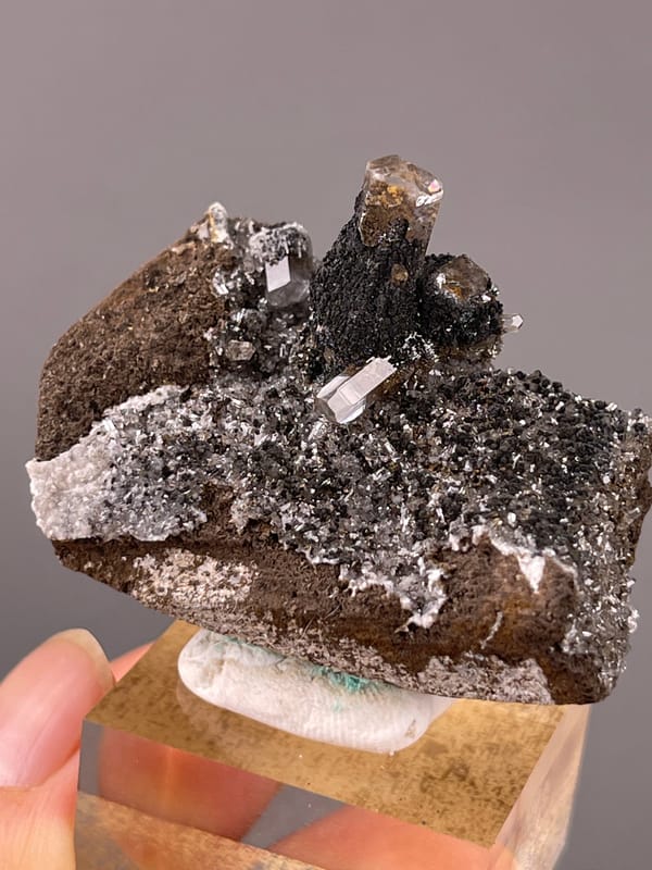 Calcite specimen from Longyan, Fujian, China bearing dark prismatic crystals with brassy coating