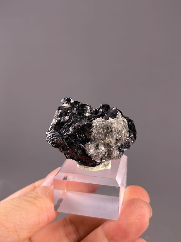Cassiterite from Xuebaoding, China: black crystals beside a silvery mica patch.