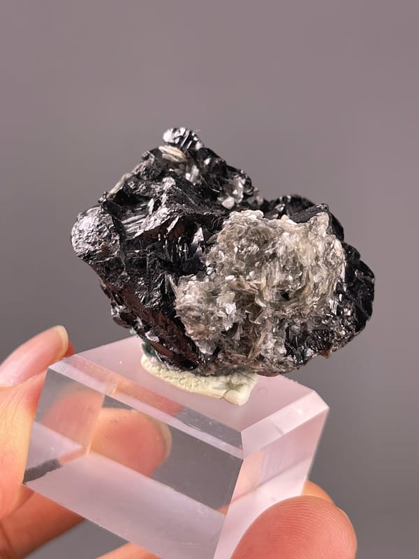 Cassiterite from Xuebaoding, China: silvery mica rosette beside black crystals.