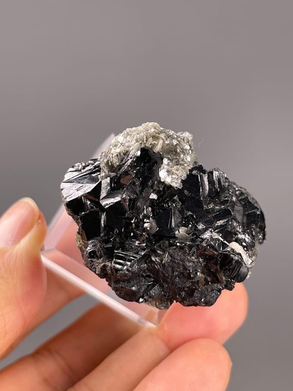 Cassiterite from Xuebaoding, China: dark crystal faces beneath the mica patch.
