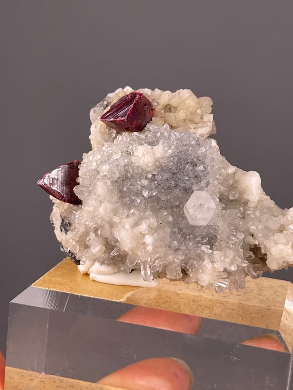 Red-brown crystals on white druse visible on cinnabar specimen from Maxianxi, Hunan, China
