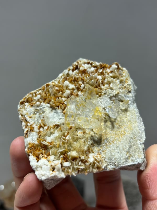Clear quartz crystal in golden mica with white feldspar from Xuebaoding, Sichuan, China, second angle