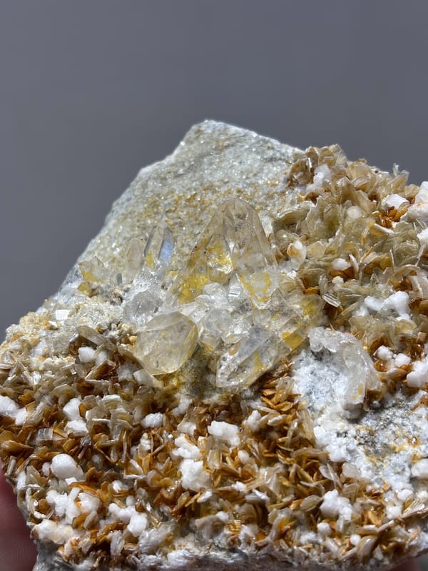 Clear quartz crystal in golden mica with white feldspar from Xuebaoding, Sichuan, China, reverse side
