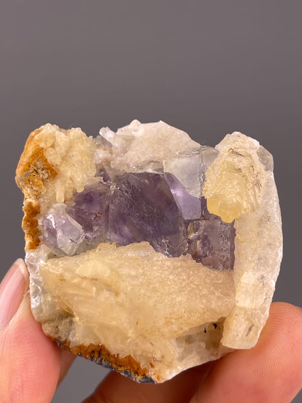 Fluorite from Fujian, China: front view of purple crystals and orange edge patches.