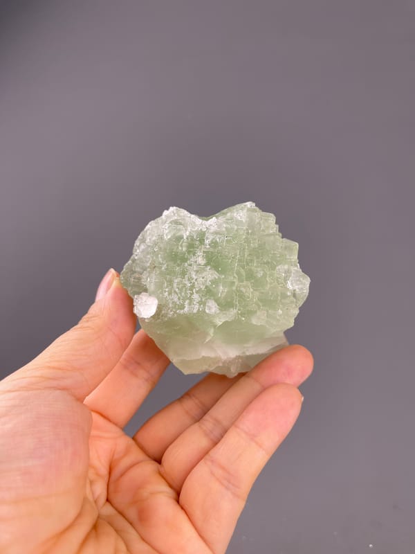 Fluorite from Fujian, China: whole pale green specimen above the palm.