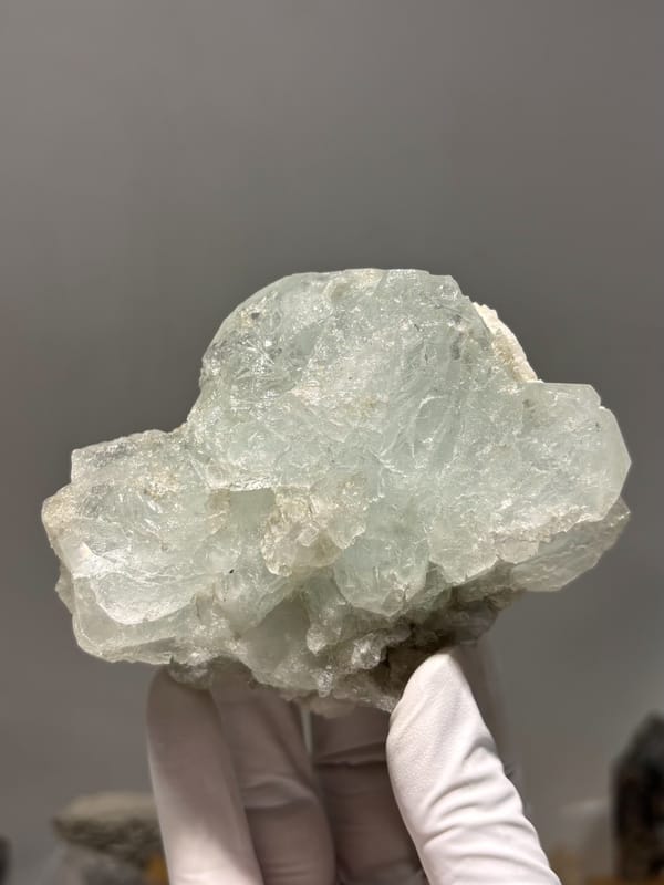Frosted pale green aquamarine block from Xuebaoding, Sichuan, China, held in gloved hand