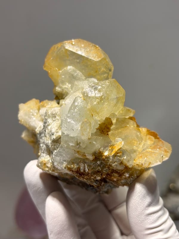 Golden-tinted aquamarine cluster with mica from Xuebaoding, Sichuan, China, held in gloved hand