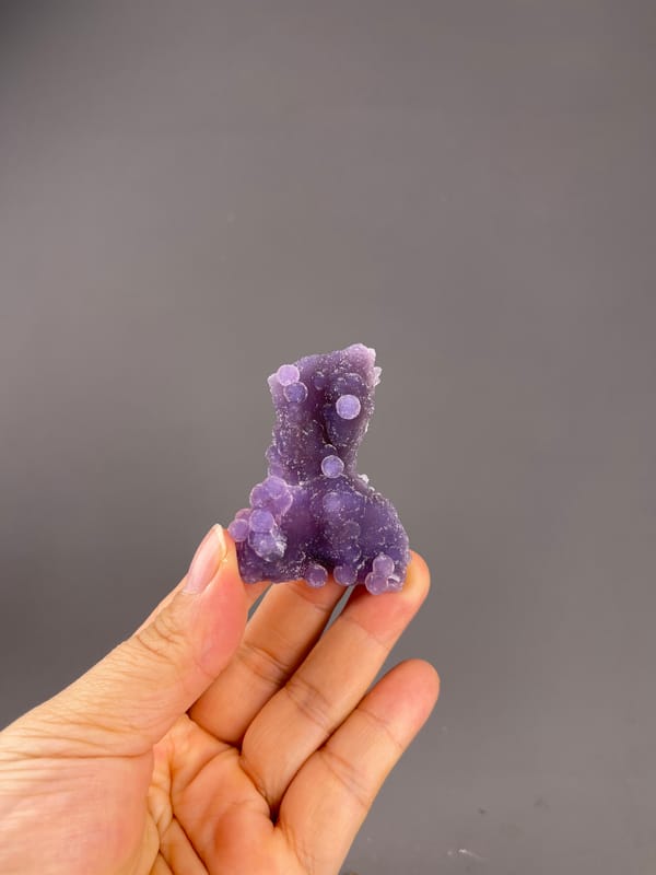 Grape Agate from Indonesia: whole purple specimen above the palm.