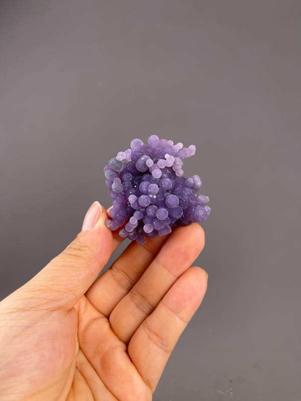 Grape Agate from Indonesia: whole purple cluster above the palm.