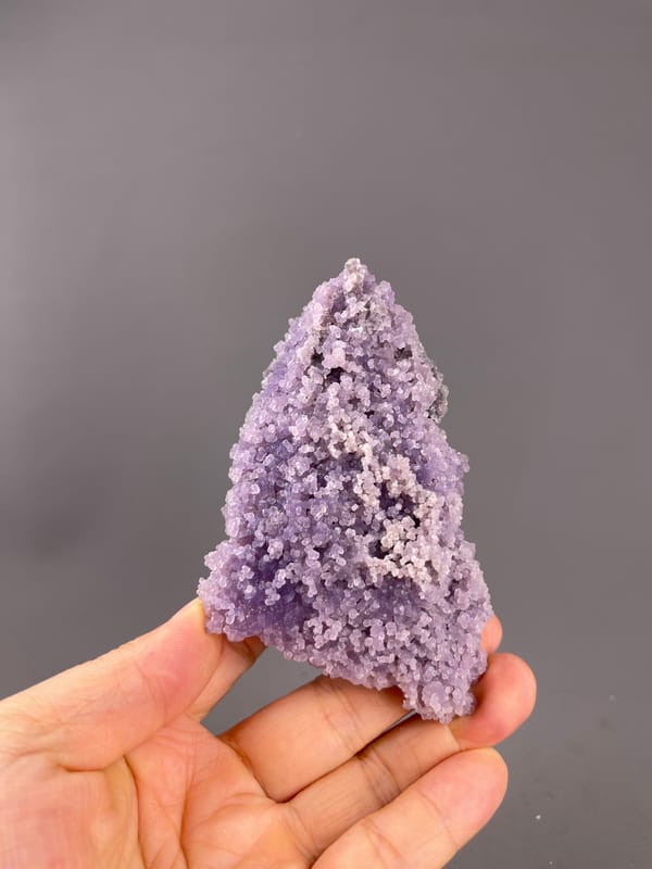 Grape Agate from Indonesia: full tapered cluster resting above fingers.