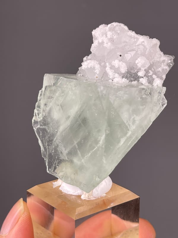 Pale green cube with white cluster visible on green fluorite specimen from Zhejiang, China
