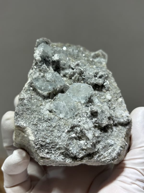 Grey matrix block dotted with pale aquamarine crystals from Xuebaoding, Sichuan, China, reverse side