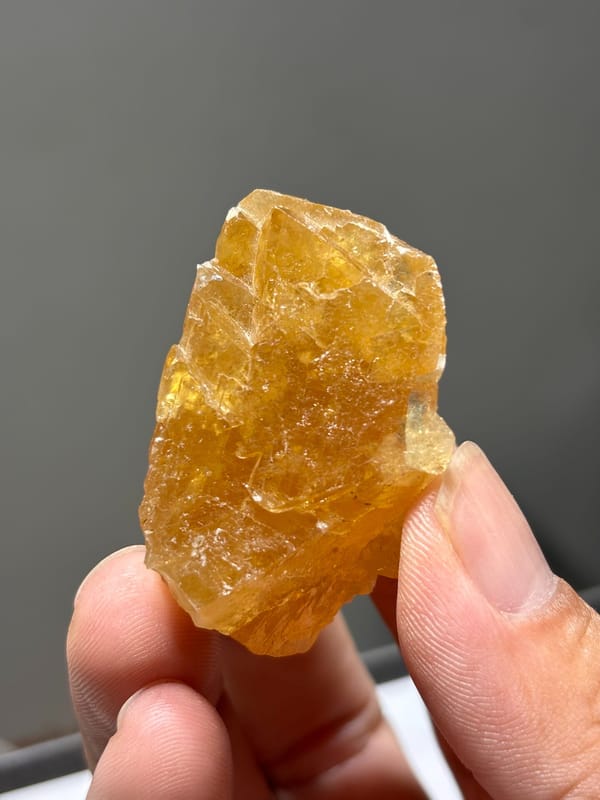 Honey-orange scheelite crystal from Xuebaoding, Sichuan, China, held in hand