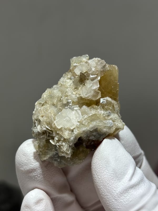 Honey scheelite with white calcite and mica from Xuebaoding, Sichuan, China, close-up of the crystal faces