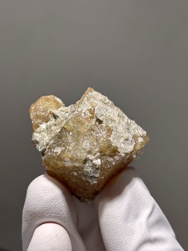 Honey scheelite group with white mica from Xuebaoding, Sichuan, China, close-up of the crystal faces