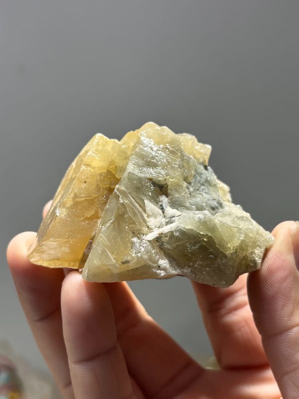 Honey scheelite group shaped like snow peak from Xuebaoding, Sichuan, China, held in hand
