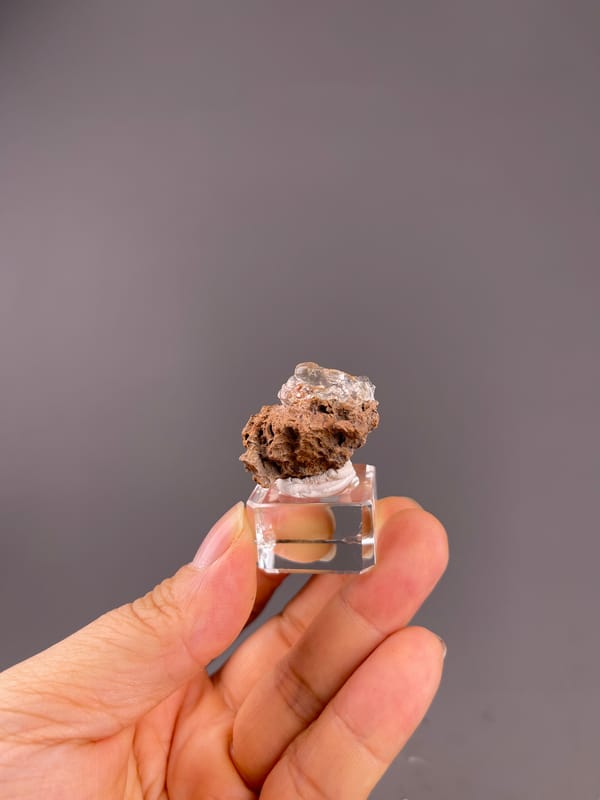 Hyalite Opal from Mexico: small mounted specimen showing brown cavities below a clear upper coating.