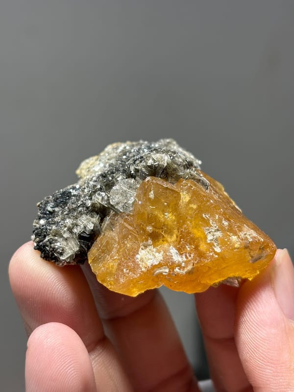 Orange scheelite floater with aquamarine and mica from Xuebaoding, Sichuan, China, held in hand