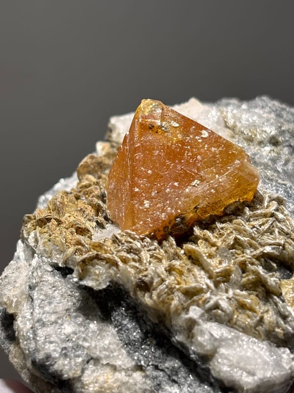 Orange scheelite on mica with fluorite at its tip from Xuebaoding, Sichuan, China