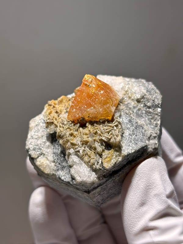 Orange scheelite on mica with fluorite at its tip from Xuebaoding, Sichuan, China, reverse side