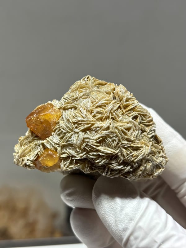 Orange scheelite crystals on tan mica block from Xuebaoding, Sichuan, China, close-up of the crystal faces