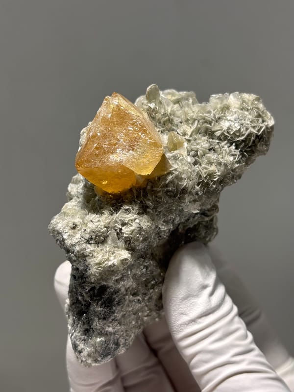 Orange scheelite crystal on dark mica block from Xuebaoding, Sichuan, China, second angle