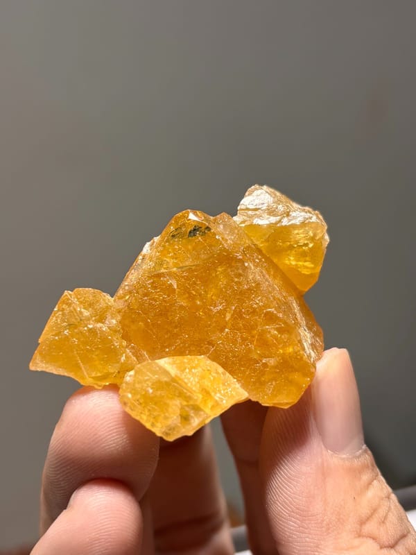 Orange scheelite crystal group from Xuebaoding, Sichuan, China, held in hand