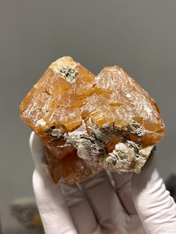 Large orange scheelite crystal group from Xuebaoding, Sichuan, China, held in gloved hand