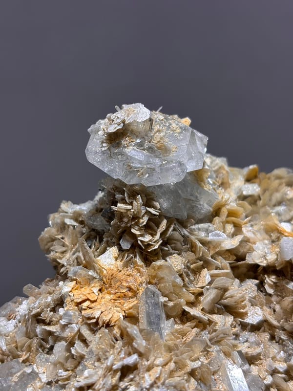 Pale aquamarine crystal atop golden mica rosette plate from Xuebaoding, Sichuan, China, close-up of the crystal faces