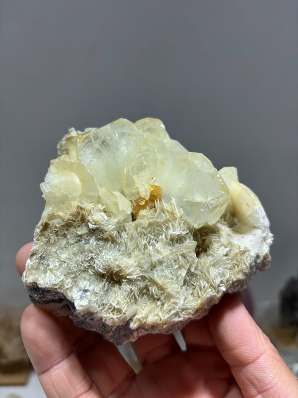 Pale aquamarine crystals over mica-and-scheelite base from Xuebaoding, Sichuan, China, held in hand
