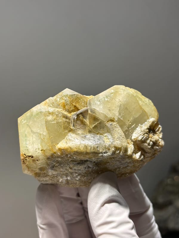 Pale aquamarine cluster on mica from Xuebaoding, Sichuan, China, held in gloved hand, view 1