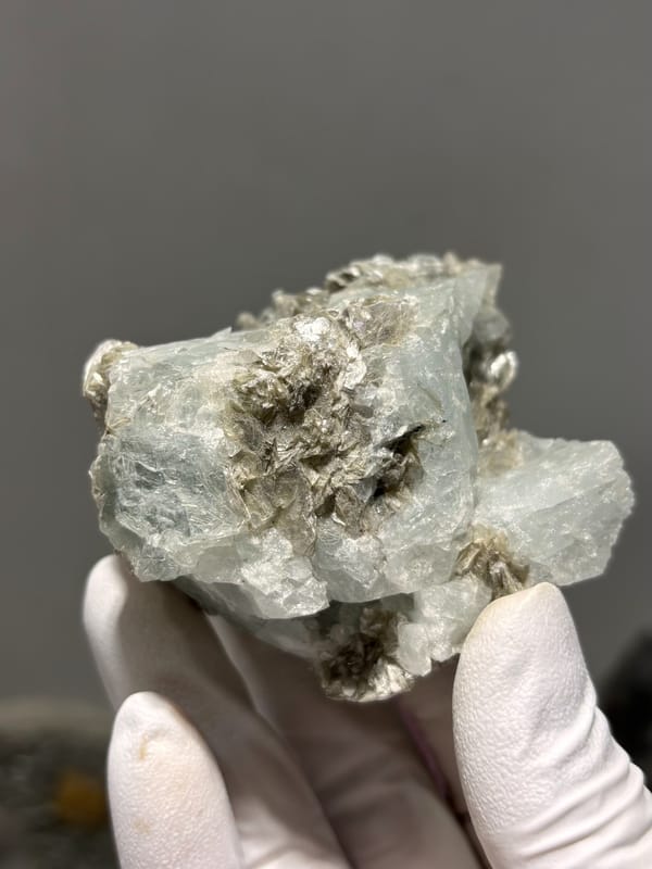 Pale blue aquamarine set in dark mica from Xuebaoding, Sichuan, China, close-up of the crystal faces