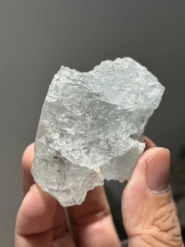 Pale blue aquamarine block with etched faces from Xuebaoding, Sichuan, China, held in hand