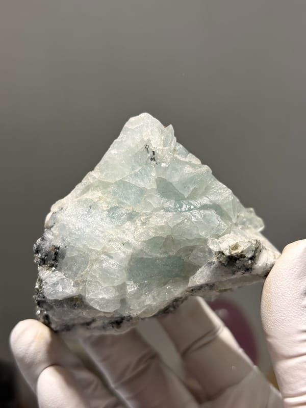 Cluster of pale blue aquamarine crystals on dark matrix from Xuebaoding, Sichuan, China, close-up of the crystal faces