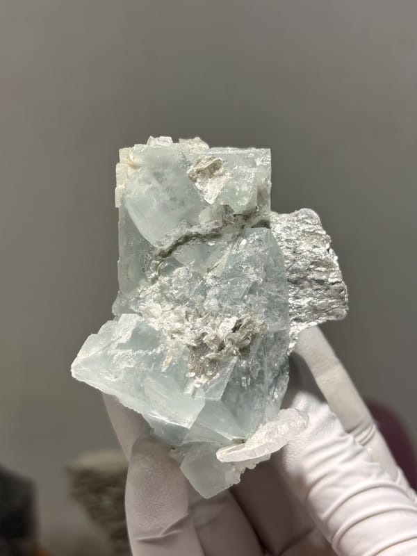 Pale green fluorite cubes with mica and albite from Xuebaoding, Sichuan, China, close-up of the crystal faces