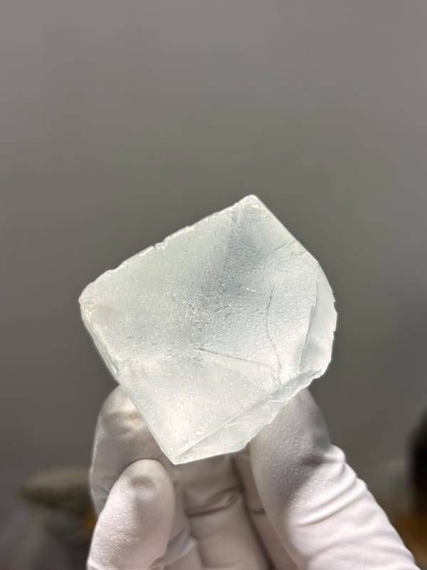 Pale green fluorite octahedron with frosted faces from Xuebaoding, Sichuan, China, held in gloved hand