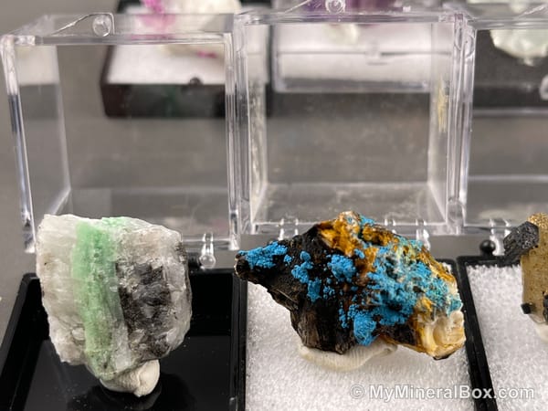 Bulk001 actual mixed mineral specimen box with about 35 different mini natural specimens in clear display boxes, including likely fluorite, quartz, aquamarine, pyrite, grape agate and other assorted minerals.