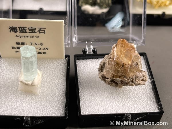 Bulk001 actual mixed mineral specimen box with about 35 different mini natural specimens in clear display boxes, including likely fluorite, quartz, aquamarine, pyrite, grape agate and other assorted minerals.