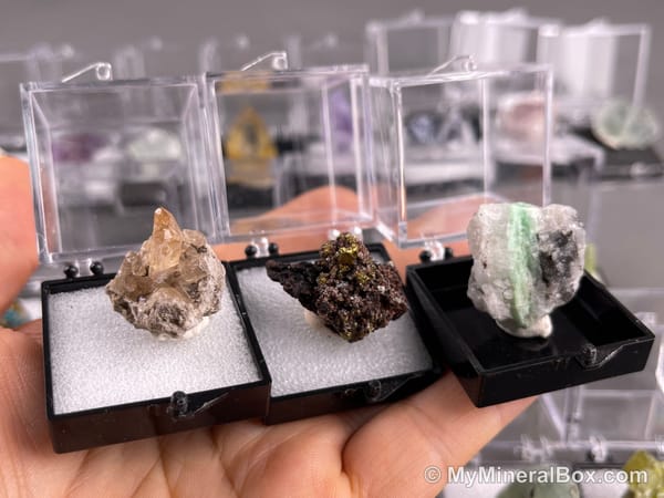 Bulk001 actual mixed mineral specimen box with about 35 different mini natural specimens in clear display boxes, including likely fluorite, quartz, aquamarine, pyrite, grape agate and other assorted minerals.