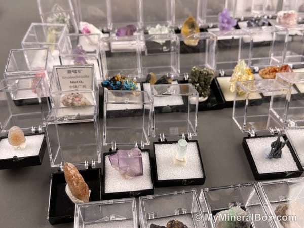 Bulk001 actual mixed mineral specimen box with about 35 different mini natural specimens in clear display boxes, including likely fluorite, quartz, aquamarine, pyrite, grape agate and other assorted minerals.