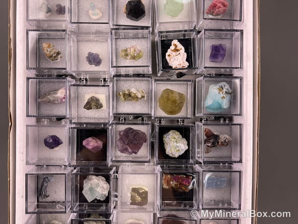 Bulk002 actual mixed mineral specimen box with approximately 35 to 40 different mini specimens in clear display boxes, including likely fluorite, quartz, aquamarine, galena, pyrite, grape agate, stibnite and other assorted minerals.