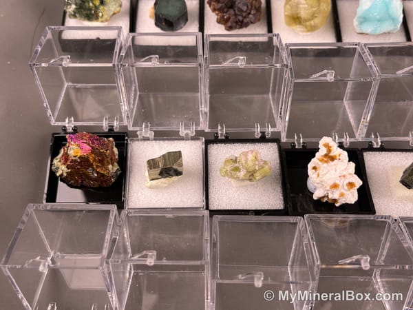 Bulk002 actual mixed mineral specimen box with approximately 35 to 40 different mini specimens in clear display boxes, including likely fluorite, quartz, aquamarine, galena, pyrite, grape agate, stibnite and other assorted minerals.