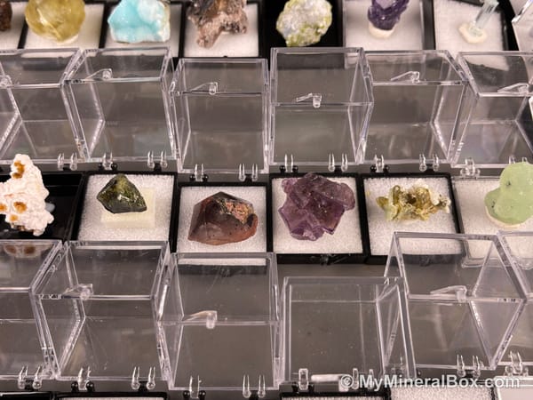 Bulk002 actual mixed mineral specimen box with approximately 35 to 40 different mini specimens in clear display boxes, including likely fluorite, quartz, aquamarine, galena, pyrite, grape agate, stibnite and other assorted minerals.