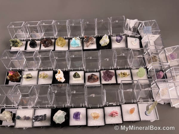Bulk002 actual mixed mineral specimen box with approximately 35 to 40 different mini specimens in clear display boxes, including likely fluorite, quartz, aquamarine, galena, pyrite, grape agate, stibnite and other assorted minerals.
