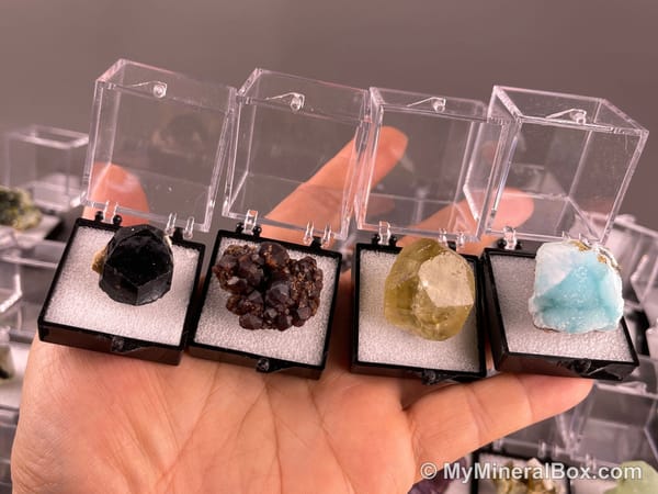 Bulk002 actual mixed mineral specimen box with approximately 35 to 40 different mini specimens in clear display boxes, including likely fluorite, quartz, aquamarine, galena, pyrite, grape agate, stibnite and other assorted minerals.