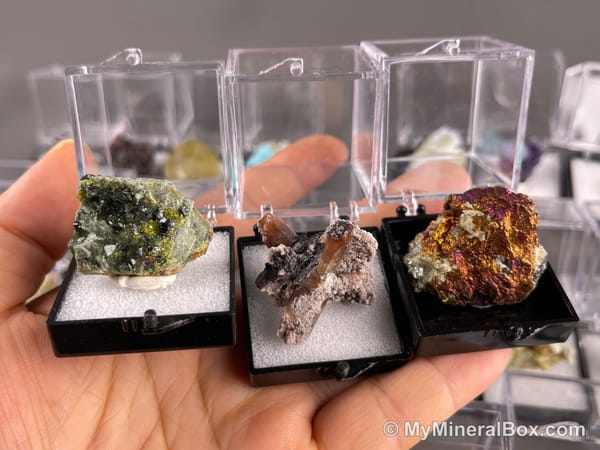 Bulk002 actual mixed mineral specimen box with approximately 35 to 40 different mini specimens in clear display boxes, including likely fluorite, quartz, aquamarine, galena, pyrite, grape agate, stibnite and other assorted minerals.