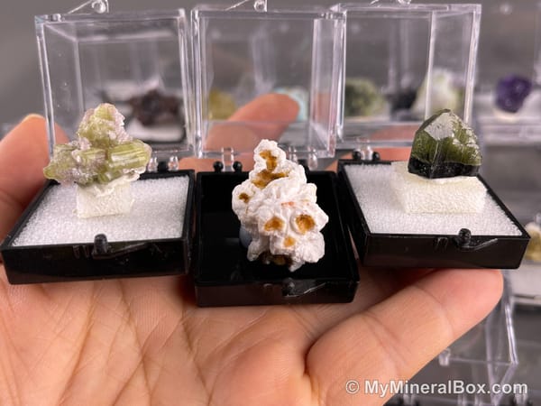 Bulk002 actual mixed mineral specimen box with approximately 35 to 40 different mini specimens in clear display boxes, including likely fluorite, quartz, aquamarine, galena, pyrite, grape agate, stibnite and other assorted minerals.