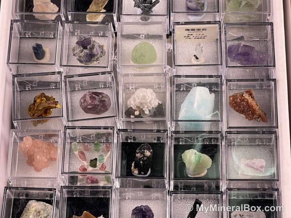 Bulk003 actual mixed mineral specimen box with about 35 different mini natural specimens, including likely fluorite, garnet, stibnite, quartz, aquamarine, tourmaline and grape agate.